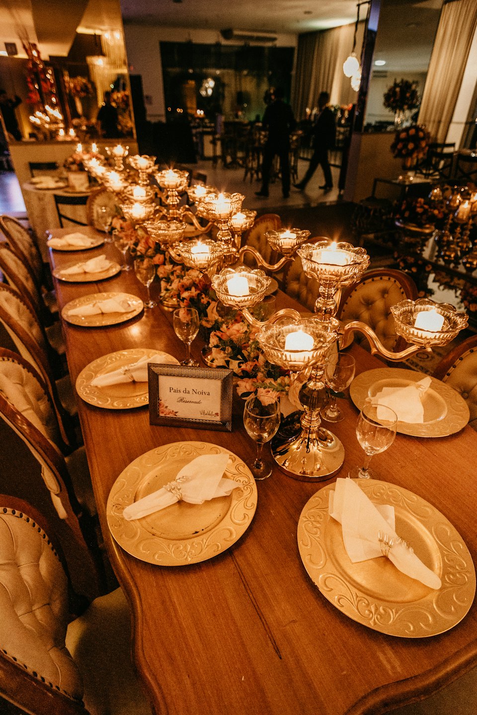 Elegant dining table set with gold chargers and lit candelabras.