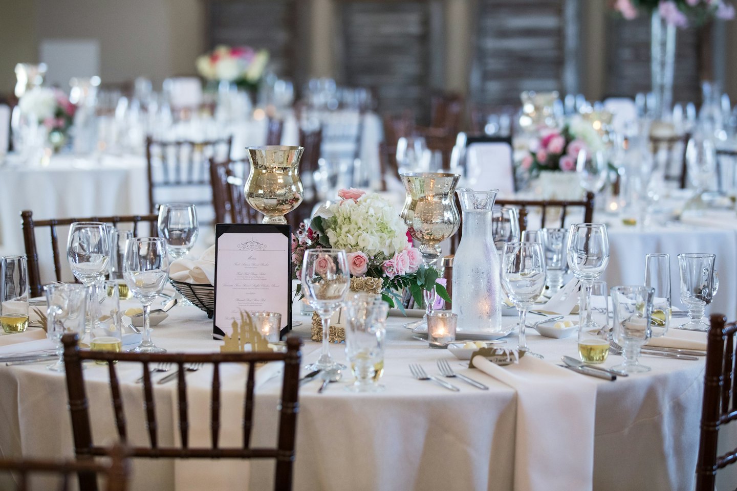 Elegant event table set with white tablecloth, glassware, and floral centerpiece.