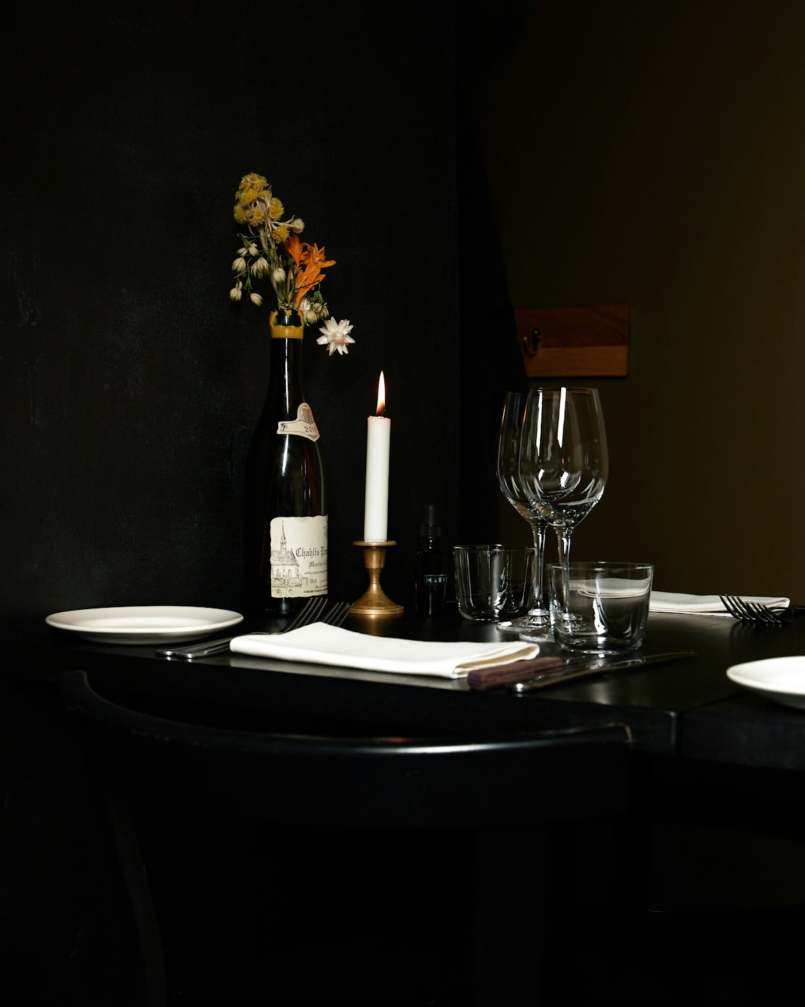 Candlelit table for two with wine and wildflowers.