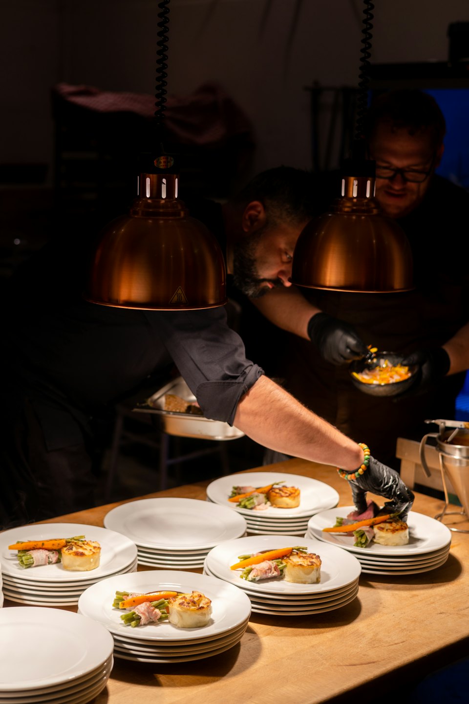Two chefs carefully plate gourmet dishes in a professional kitchen.